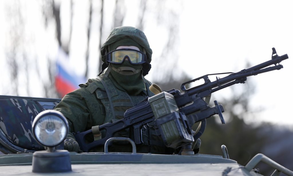 A military personnel member, believed to be a Russian serviceman, stands guard on a military vehicle outside the territory of a Ukrainian military unit in the village of Perevalnoye outside Simferopol March 3, 2014. Ukraine mobilised for war on Sunday and Washington threatened to isolate Russia economically after President Vladimir Putin declared he had the right to invade his neighbour in Moscow's biggest confrontation with the West since the Cold War. Russian forces have already bloodlessly seized Crimea, an isolated Black Sea peninsula where Moscow has a naval base. REUTERS/David Mdzinarishvili (UKRAINE - Tags: POLITICS MILITARY CIVIL UNREST)
